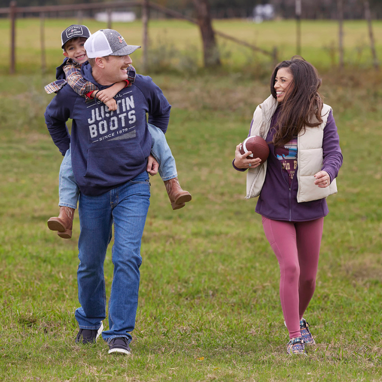 A family walking on a field carrying a football and looking at each other.